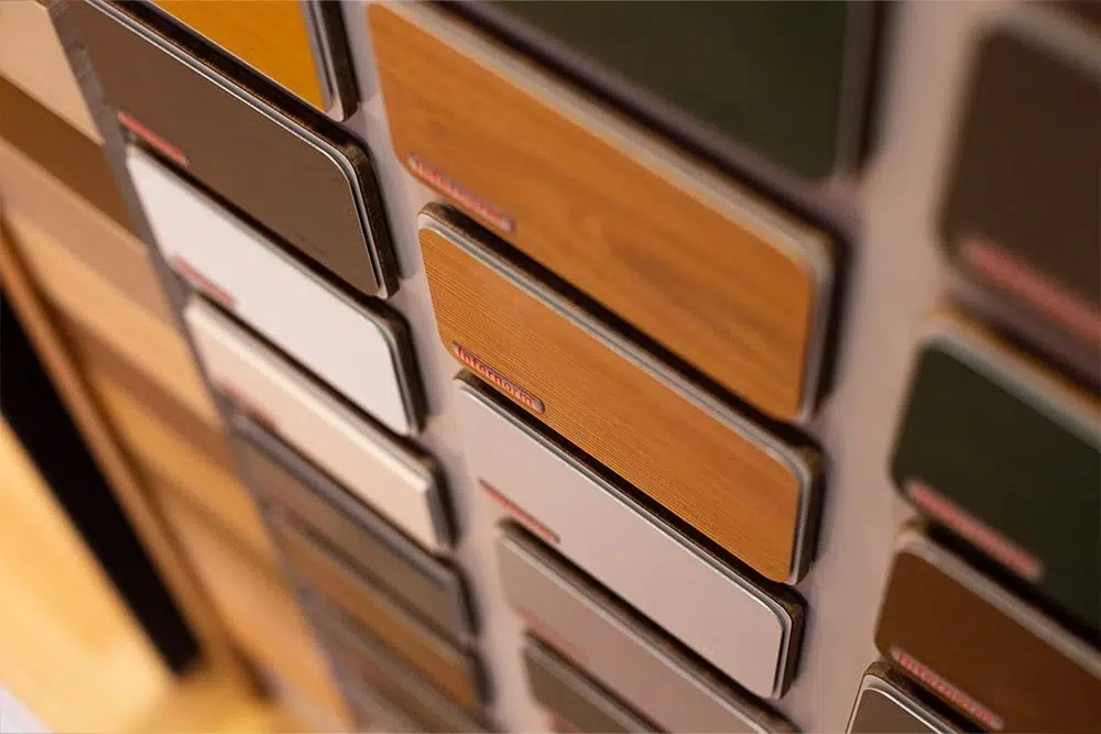 Ausstellungswand mit vertikal angeordneten Proben in verschiedenen Holz- und Farbdekoren.