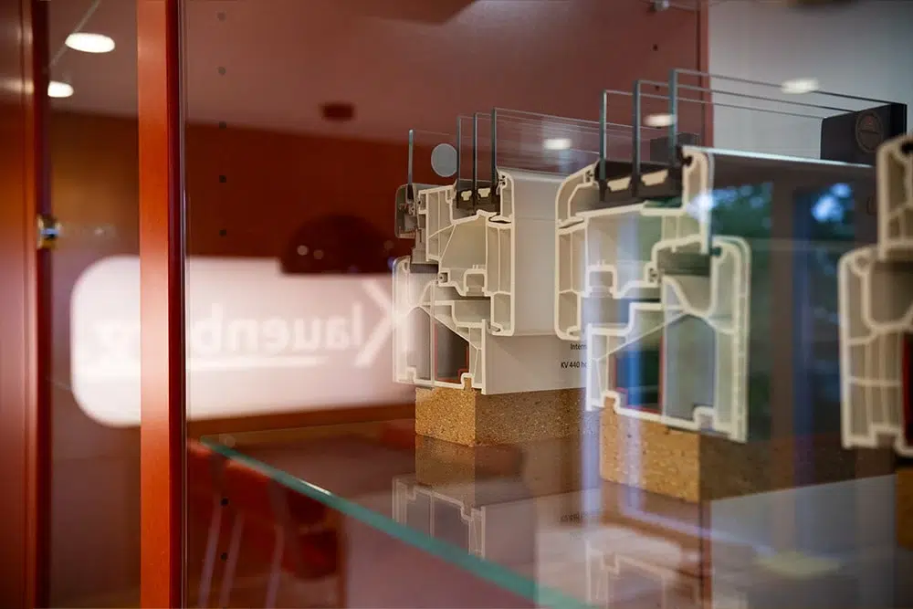 Querschnitte von Kunststofffensterprofilen in einer Glasvitrine in einem Ausstellungsraum.