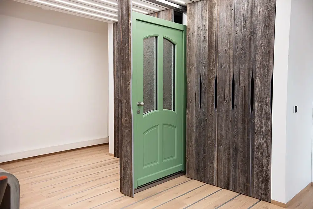 Grüne Innentür mit satiniertem Glas, eingelassen in rustikale dunkle Holzpaneele in einem modernen Raum mit hellem Holzboden.